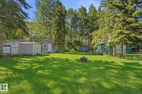 Expansive grassy yard area with mature evergreen trees and a visible detached garage - 1410 47436 Range Rd. 15, Rural Leduc County, AB 