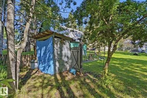 Wood-paneled shed with a metal roof and a wooden gate, situated on a grassy slope - 1410 47436 Range Rd. 15, Rural Leduc County, AB 