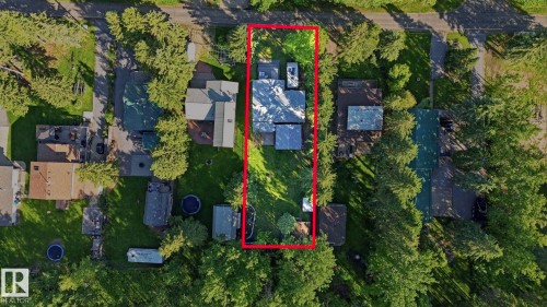 Overhead perspective of a residential property featuring a gray-roofed structure surrounded by mature trees and green landscaping - 1410 47436 Range Rd. 15, Rural Leduc County, AB 