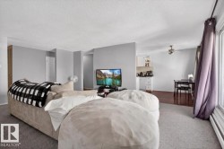 Open-concept living area featuring light gray wall paint, textured ceiling, and a large window with vertical blinds - 