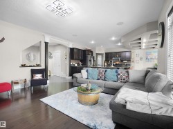 Open-concept kitchen featuring a large island with a stainless steel dishwasher, dark cabinetry, and a granite-look countertop - 