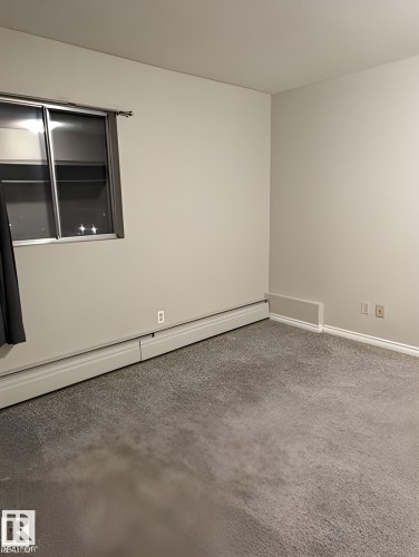 Carpeted room featuring light gray walls and baseboard heating - 611 12831 66 Street, Edmonton, AB 