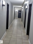 Hallway with light gray walls, dark door frames, and sconce lighting - 