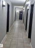Hallway with light gray walls, dark door frames, and sconce lighting - 611 12831 66 Street, Edmonton, AB 