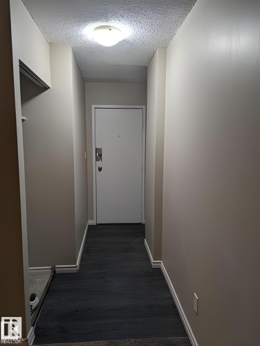 Entryway featuring wood-finish flooring, light tan wall color, a flush-mount ceiling light fixture, and white baseboards - 611 12831 66 Street, Edmonton, AB 