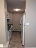 Galley-style kitchen featuring white cabinetry with black hardware, a white electric range, and a white refrigerator - 611 12831 66 Street, Edmonton, AB 