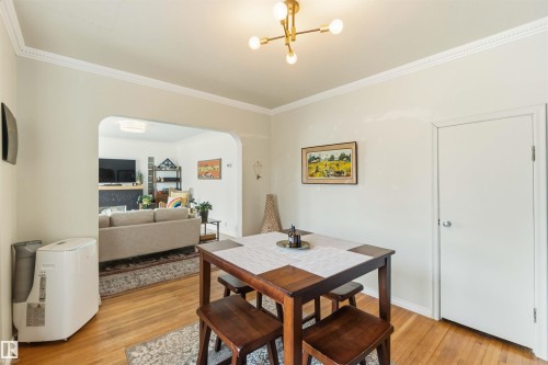 Hardwood flooring throughout featuring a modern light fixture and crown molding - 6036 106 Street, Edmonton, AB 