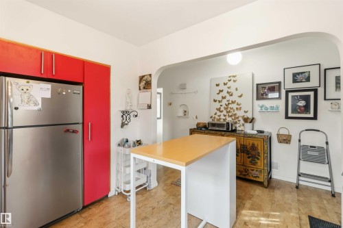 Kitchen featuring vibrant red cabinetry, stainless steel refrigerator, and wood-finish flooring - 6036 106 Street, Edmonton, AB 