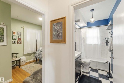 Bathroom featuring black and white checkerboard flooring, subway tile surround, and a modern pendant light fixture - 6036 106 Street, Edmonton, AB 