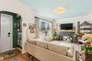 Living area featuring wood-finish flooring, a decorative fireplace with a dark-toned surround, a front entry door with a decorative glass insert, and a large window - 6036 106 Street, Edmonton, AB 