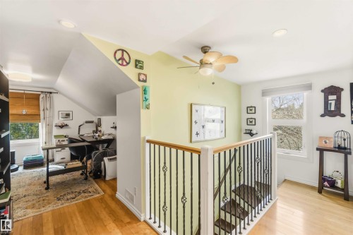 Hardwood flooring extending throughout an upper-level landing featuring a wood and wrought iron staircase - 6036 106 Street, Edmonton, AB 