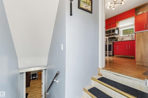 Stairway with wood-finish handrail leading to a lower level featuring wood-finish flooring - 6036 106 Street, Edmonton, AB 