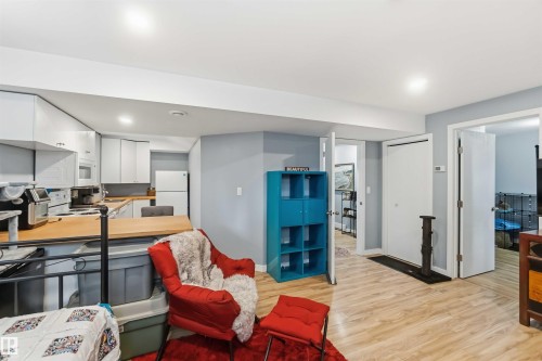 Open-concept living area featuring wood-finish flooring, a kitchen with white cabinetry and a built-in microwave, and recessed lighting - 6036 106 Street, Edmonton, AB 