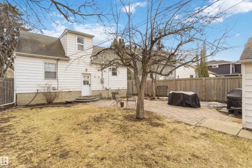 Expansive backyard featuring a paver patio area, mature trees, and a wooden privacy fence - 6036 106 Street, Edmonton, AB 