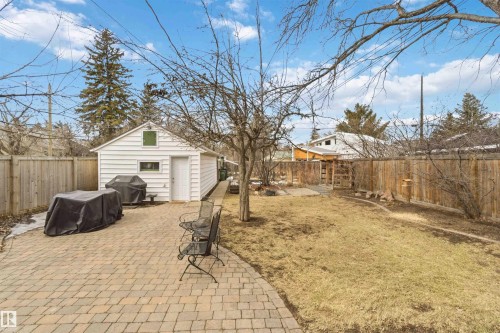 Spacious backyard featuring a paver patio and a detached garage with horizontal siding - 6036 106 Street, Edmonton, AB 