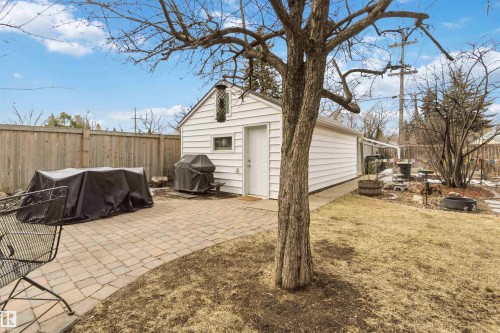 Detached white garage with a pitched roof and a side door, complemented by a paver patio area - 6036 106 Street, Edmonton, AB 
