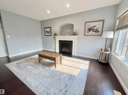 Living area featuring a central fireplace with an arched alcove, dark wood-finish flooring, and light-toned walls - 