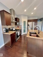 Kitchen featuring stainless steel appliances, dark wood cabinetry, and granite countertops - 