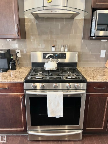 Stainless steel range with gas cooktop and matching overhead ventilation hood - 108 South Creek Wynd, Stony Plain, AB 