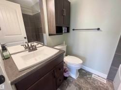 Bathroom featuring a dark wood-finish vanity with an integrated white sink, a dark countertop, and a coordinating dark wood-finish wall cabinet - 