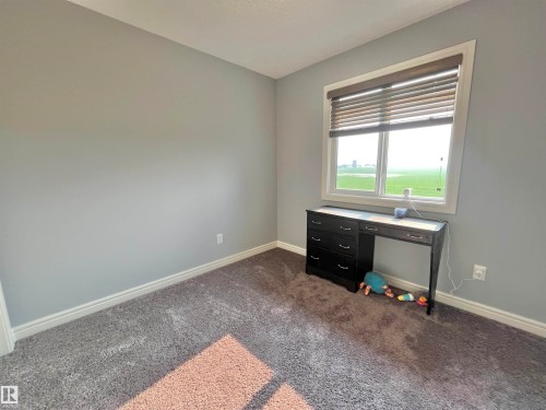 Bedroom with window featuring exterior landscape, light gray wall paint, white trim, and gray carpet flooring - 108 South Creek Wynd, Stony Plain, AB 