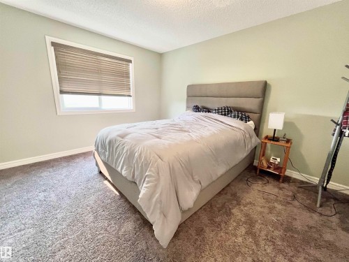 Bedroom with light green walls and textured carpeting - 108 South Creek Wynd, Stony Plain, AB 