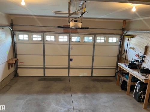 Two-car garage featuring a sectional overhead door with upper window inserts and an automatic opener - 108 South Creek Wynd, Stony Plain, AB 