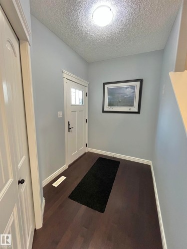 Entryway featuring a paneled door with frosted glass, wood-finish flooring, and light blue wall paint - 108 South Creek Wynd, Stony Plain, AB 