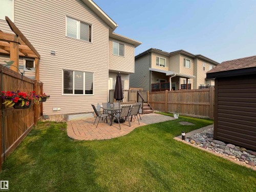 Fenced backyard with a curved brick paver patio, a freestanding shed with horizontal siding, and a landscaped rock bed - 108 South Creek Wynd, Stony Plain, AB 