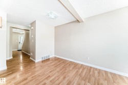 Expansive interior room featuring light wood-finish flooring, neutral wall paint, white baseboards, and a white ceiling with a flush-mount light fixture - 