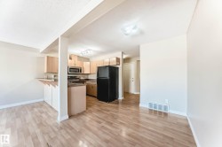 Bright interior featuring wood-finish flooring, recessed lighting, and a kitchen with light wood cabinetry - 