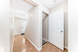 Entryway featuring light wood-finish flooring, white baseboards, and a white six-panel door leading to an under-stair storage area - 
