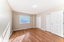 Bright room featuring wood-finish flooring, neutral wall tones, and multiple bi-fold closet doors - 