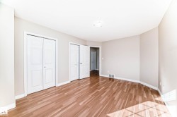 Expansive room featuring wood-finish flooring, light-toned wall paint, and white trim - 