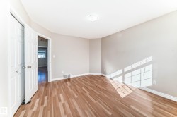 Spacious room featuring wood-finish flooring, light neutral wall paint, and white baseboards - 
