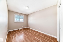 Room featuring wood-finish flooring, a single window with white blinds, and a flush-mount ceiling light - 