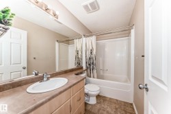 Bathroom featuring a single vanity with an oval sink, laminate countertop, and wood-finish cabinetry - 
