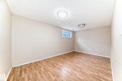 Spacious room with light wood-finish flooring, neutral wall tones, and overhead flush-mount lighting fixtures - 
