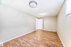 Spacious room featuring wood-finish flooring, neutral-toned walls, and two flush-mount ceiling light fixtures - 