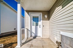 Front entry featuring a paneled door with glass inserts, an exterior wall lantern, and a covered porch - 