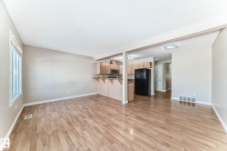 Bright open-concept living area featuring wood-finish flooring, a large window, neutral wall tones, and recessed lighting - 