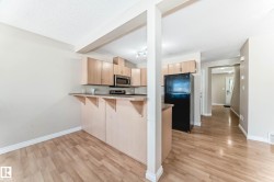 Kitchen featuring wood-finish flooring, light-toned cabinetry, stainless steel microwave, and track lighting - 