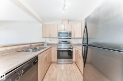 U-shaped kitchen featuring light wood cabinetry, laminate countertops, and stainless steel appliances including a refrigerator, range, microwave, and dishwasher - 