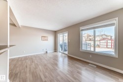 Open-concept living area with wood-finish flooring, neutral wall tones, and white trim - 