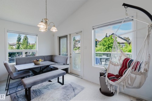 Bright dining area featuring a vaulted ceiling, a chandelier light fixture, and white trim windows - 1743 Melrose Crescent Sw, Edmonton, AB 