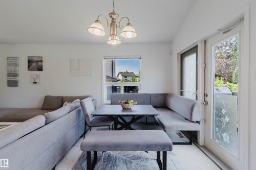 Dining area featuring a built-in banquette, rectangular table with an X-base, and a three-light chandelier - 1743 Melrose Crescent Sw, Edmonton, AB 
