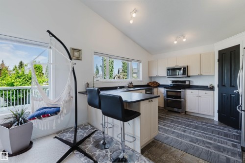 Modern kitchen featuring light-toned cabinetry, dark countertops, and stainless steel appliances - 1743 Melrose Crescent Sw, Edmonton, AB 