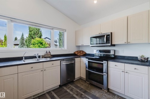 Kitchen with light-toned cabinetry and dark countertops - 1743 Melrose Crescent Sw, Edmonton, AB 