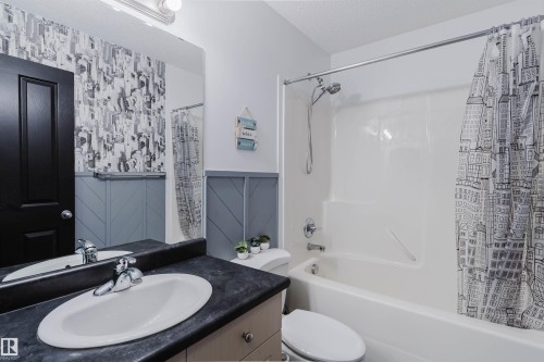 Full bathroom featuring a white tub/shower combination, a vanity with an integrated sink, a dark countertop, and a large wall-mounted mirror - 1743 Melrose Crescent Sw, Edmonton, AB 
