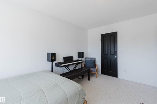 White wall interiors with textured light-colored carpeting, featuring a contrasting dark paneled door - 1743 Melrose Crescent Sw, Edmonton, AB 